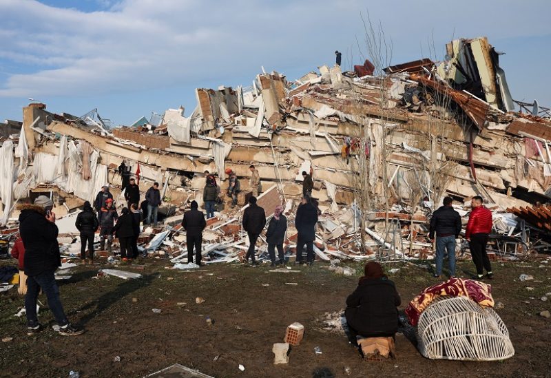 People look at the destruction as rescuers search for survivors in the rubble following an earthquake in Hatay, Turkey, February 7, 2023. REUTERS/Umit Bektas