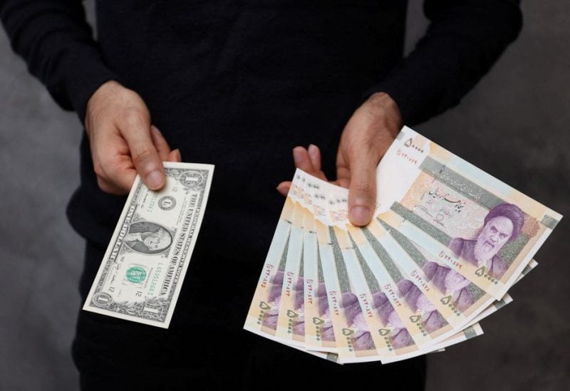 A currency dealer poses for a photo with a U.S one dollar bill and the amount being given when converting it into Iranian rials in an exchange shop in Tehran, Iran December 25, 2022. Majid Asgaripour/WANA (West Asia News Agency) via REUTERS