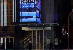 People walk past an electric board showing Nikkei index at a business district in Tokyo, Japan December 20, 2022. REUTERS