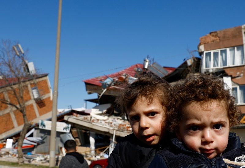 Children sit next to a damaged building in the aftermath of a deadly earthquake, in Kahramanmaras, Turkey February 9, 2023. REUTERS/Suhaib Salem