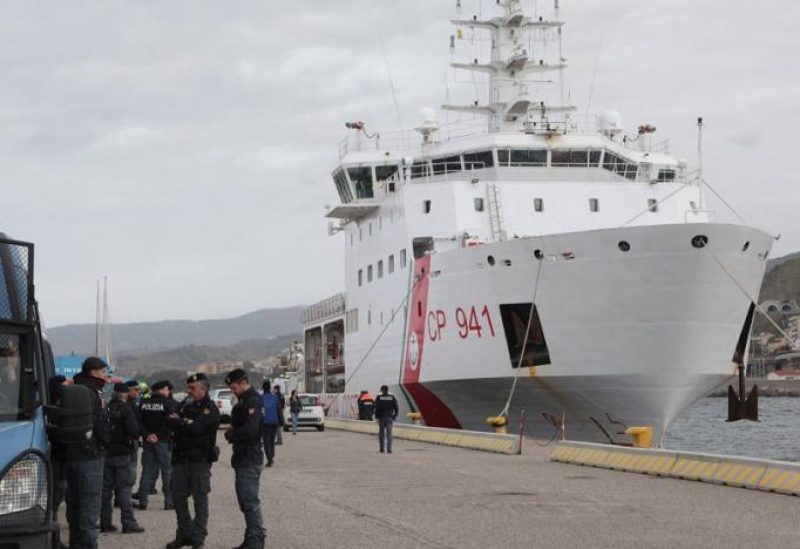 Police officers gather as the Diciotti offshore patrol vessel (R) carrying 584 migrants rescued at sea docks at a port in Reggio Calabria, southern Italy, 11 March 2023. (EPA)
