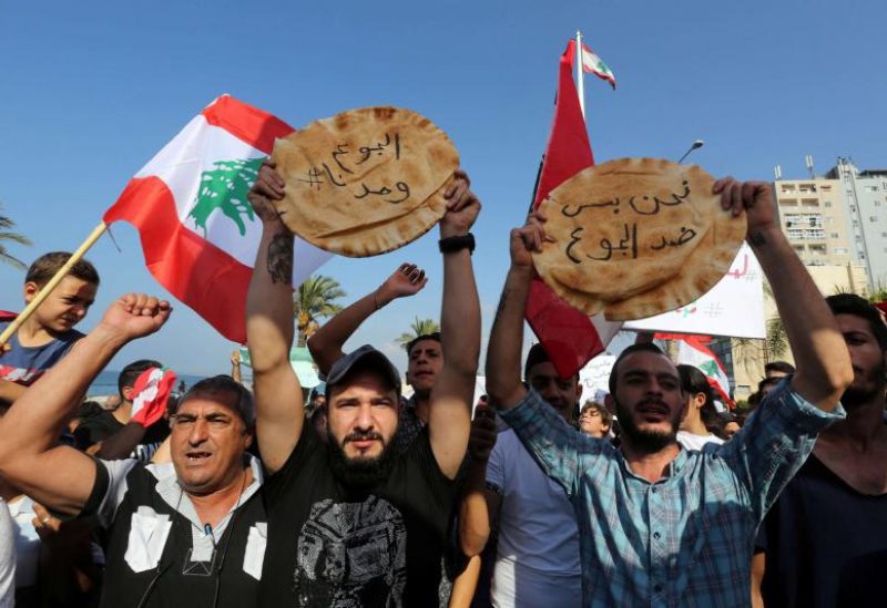 Demonstrators hold loaves of bread that read “we are only against hunger” and “hunger united us” during an anti-government protest in Tyre, Lebanon. (REUTERS)