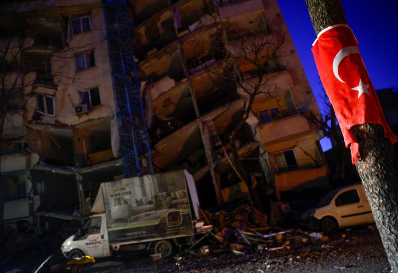 A Turkish flag is seen on a pole in front of a collapsed building, as rescue continues in the aftermath of a deadly earthquake in Kahramanmaras, Turkey February 12, 2023. REUTERS/Guglielmo Mangiapane