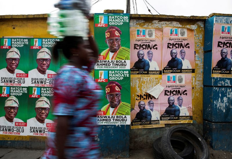 A woman walks past election posters of APC party candidates including presidential hopeful Bola Ahmed Tinubu in Lagos, Nigeria on February 24, 2023. REUTERS/James Oatway