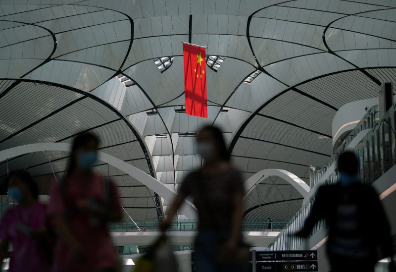 People wearing face masks following the coronavirus disease (COVID-19) outbreak walk under a Chinese flag at Beijing Daxing International Airport in Beijing, China July 24, 2020. REUTERS/Thomas Suen/File Photo