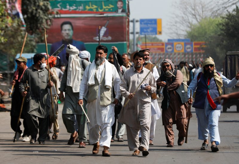 Supporters of former Pakistani Prime Minister Imran Khan, carry sticks as they walk towards Khan's house, in Lahore, Pakistan March 16, 2023. REUTERS/Akhtar Soomro