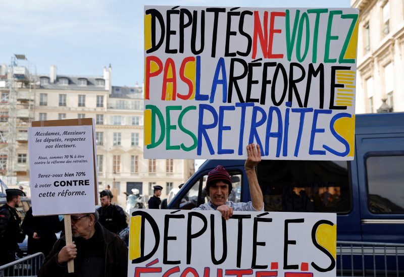 Protesters, holding a placard which reads "Members of parliament, do not vote the pension reform bill", gather in front of the National Assembly in Paris as French parliament set to vote on pensions reform bill, France, March 16, 2023. REUTERS/Pascal Rossignol