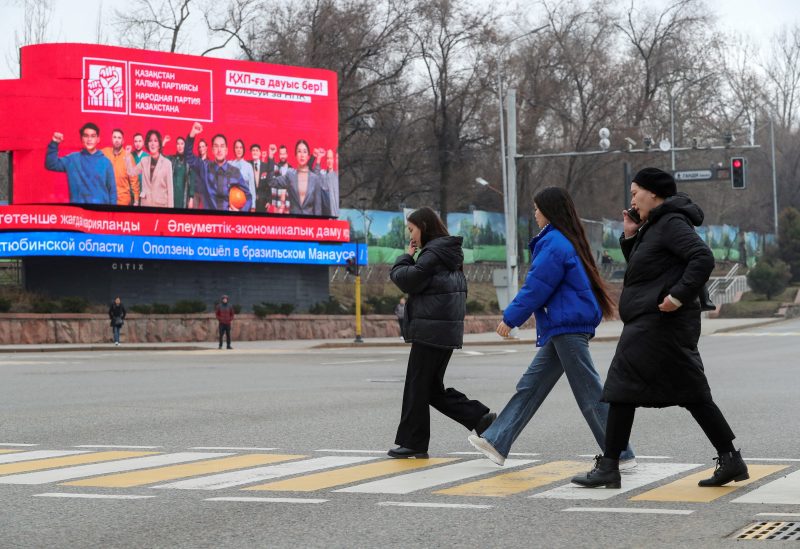 Pedestrians cross a road near an electronic board promoting the People's Party of Kazakhstan ahead of the upcoming parliamentary elections in Almaty, Kazakhstan, March 14, 2023 REUTERS/Pavel Mikheyev/File Photo