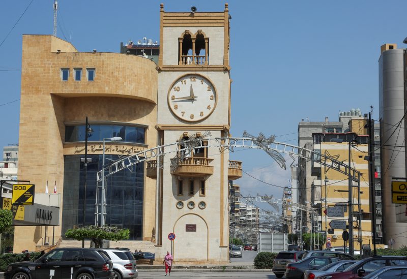A woman walks near a clock tower that indicates the time in Jdeideh, Lebanon March 26, 2023. REUTERS/Mohamed Azakir