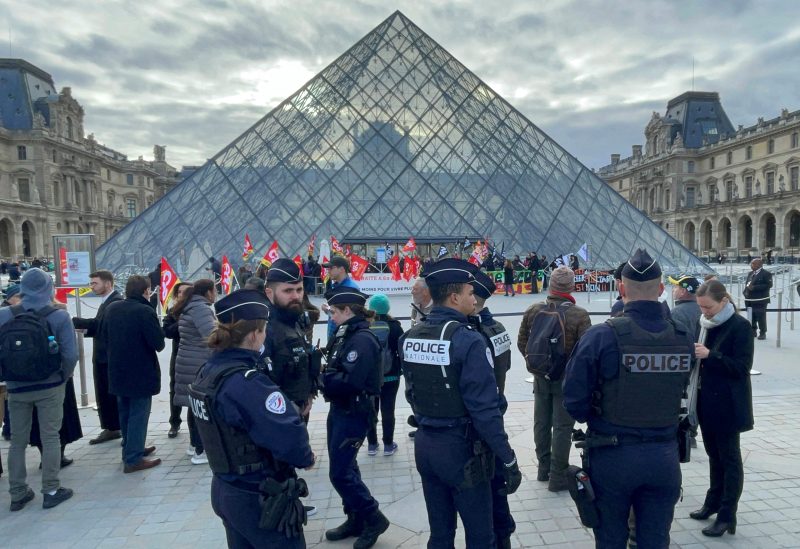 French police look on as protesters holding French CGT labour union flags in front of the glass Pyramid block the entrance of the Louvre museum to protest against the French government's pension reform, in Paris, France, March 27, 2023. REUTERS/Marco Trujillo