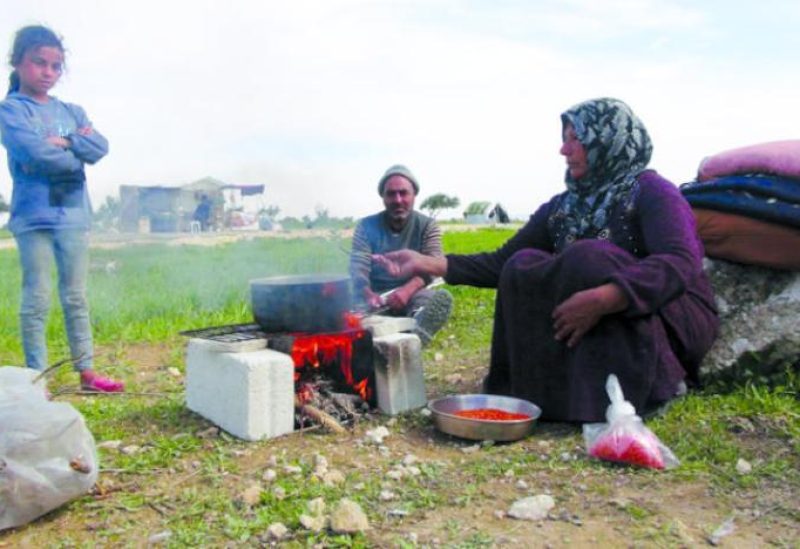 A housewife cooks food over a fire in a shelter in the city of Jisr al-Shughour. (Asharq Al-Awsat)