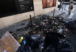 A woman stands next to burnt garbages in a street the day after clashes during protests over French government's pension reform in Paris, France, March 24, 2023. REUTERS/Yves Herman