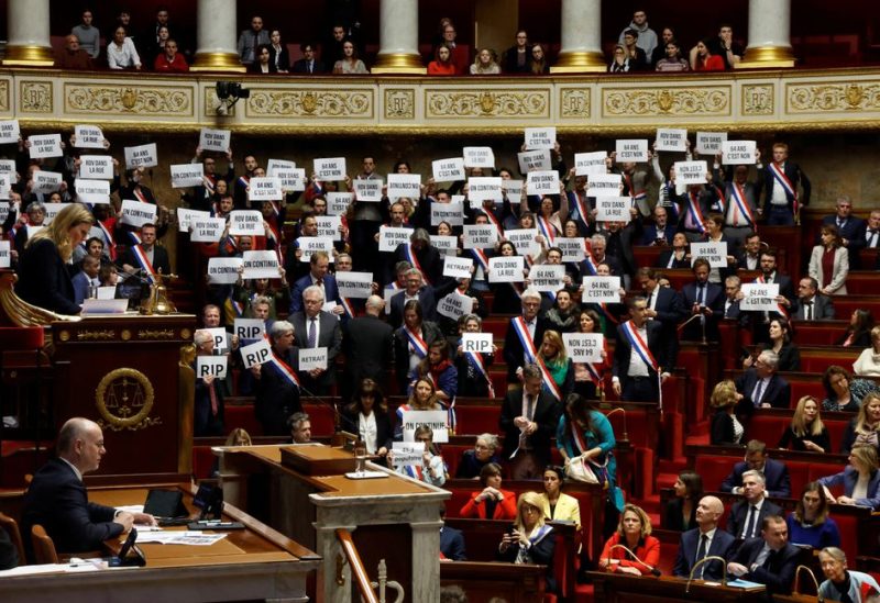 Members of parliament of the left hold placards after the result of the vote on the first motion of no-confidence against the French government, tabled by centrist group Liot, after the use by French government of the article 49.3, a special clause in the French Constitution, to push the pensions reform bill through the National Assembly without a vote by lawmakers, at the National Assembly in Paris, France, March 20, 2023 - REUTERS