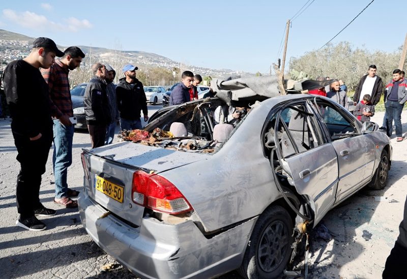 People look at a damaged car where three Palestinian militants were killed during an Israeli operation, near Jenin, in the Israeli-occupied West Bank, March 9, 2023. REUTERS/Raneen Sawafta