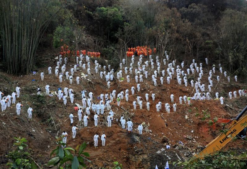 Rescue workers stand in a silent tribute at the site to mourn the victims of a China Eastern Airlines Boeing 737-800 plane, flight MU5735, that crashed in Wuzhou, Guangxi Zhuang Autonomous Region, China, March 27, 2022. cnsphoto via REUTERS