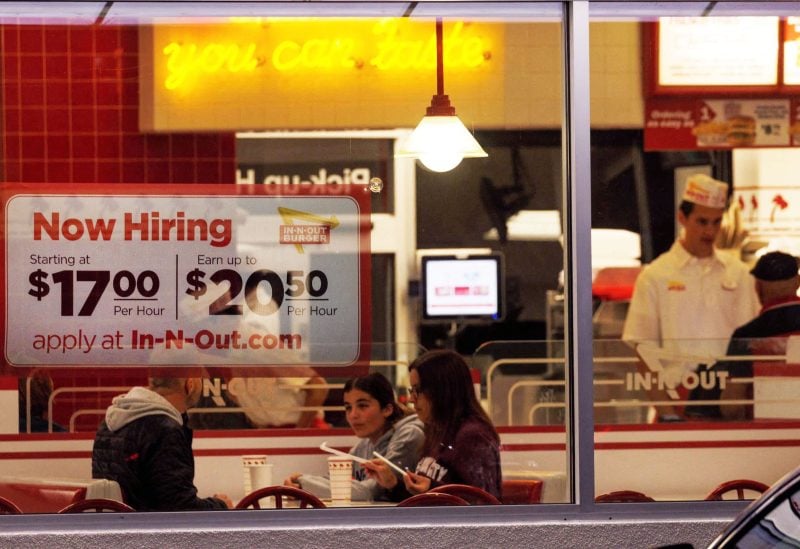 A "Now hiring" sign is displayed on the window of an IN-N-OUT fast food restaurant in Encinitas, California, U.S., May 9, 2022. REUTERS/Mike Blake