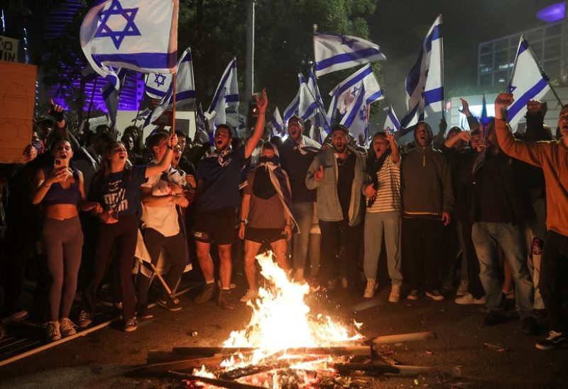 Israeli protesters chant in front of a burning fire at a demonstration against Israeli Prime Minister Benjamin Netanyahu and his nationalist coalition government's plan for judicial overhaul, in Tel Aviv, Israel, March 27, 2023. REUTER