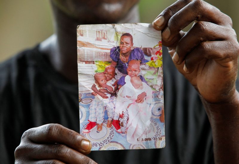 Steven Mwiti holds a photograph of his late wife Joan Bahati, a follower of a Christian cult named "Good News International Church", who believed they would go to heaven, if they starved themselves to death alongside his six children in Shakahola, outside the Malindi sub district hospital mortuary in Malindi, Kilifi county, Kenya April 26, 2023. REUTERS/Monicah Mwangi