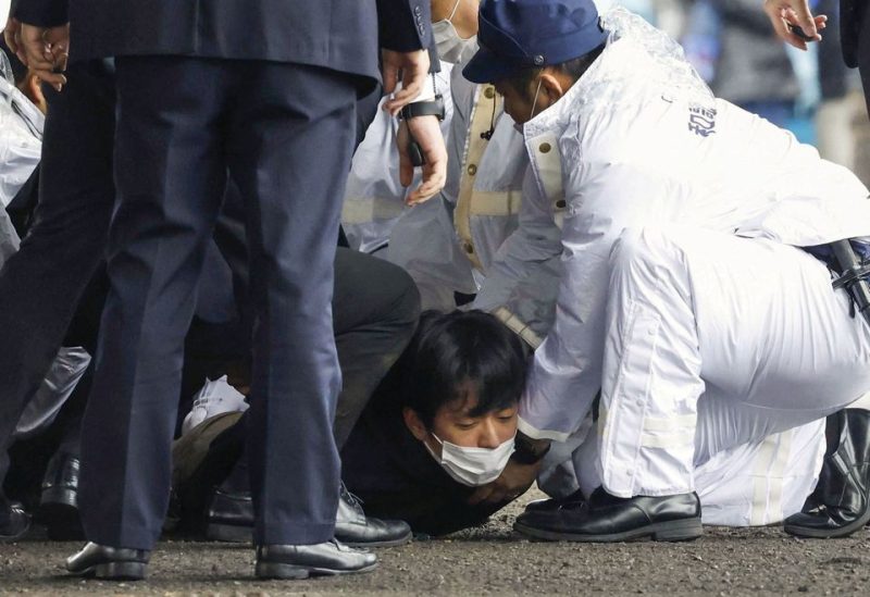 A man, believed to be a suspect who threw a pipe-like object near Japanese Prime Minister Fumio Kishida during his outdoor speech, is held by police officers at Saikazaki fishing port in Wakayama, Wakayama Prefecture, south-western Japan April 15, 2023 - REUTERS