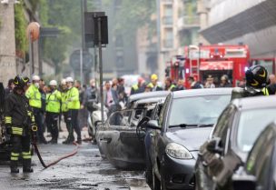 A firefighter stands next to a burnt vehicle following an explosion in the centre of Milan, Italy, May 11, 2023. REUTERS