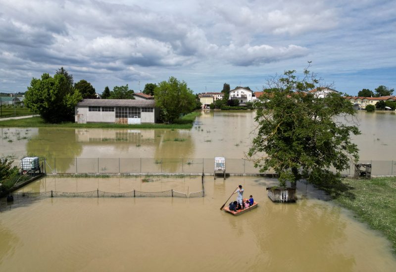 Residents use a boat to navigate through flood water after heavy rains hit Italy's Emilia Romagna region, in San Pancrazio near Ravenna, Italy, May 18, 2023. REUTERS/Antonio Denti