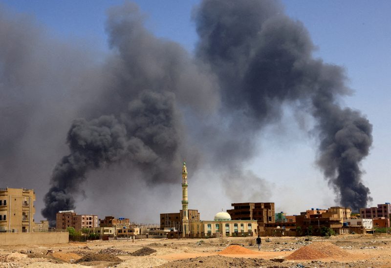 A man walks while smoke rises above buildings after aerial bombardment, during clashes between the paramilitary Rapid Support Forces and the army in Khartoum North, Sudan, May 1, 2023. REUTERS/Mohamed Nureldin Abdallah