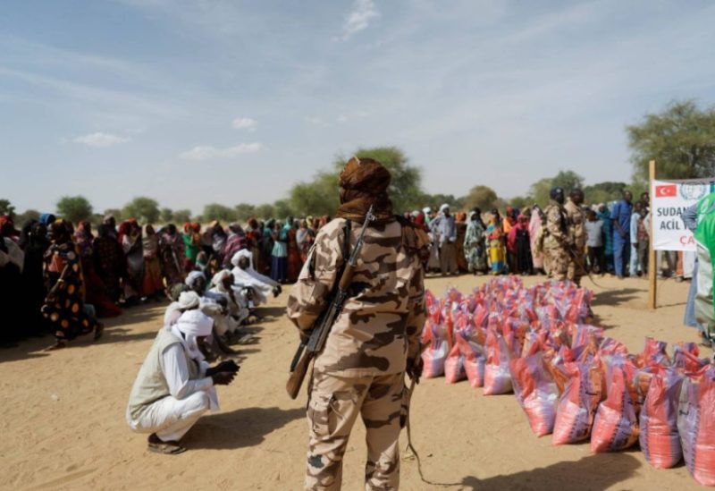 A soldier stands as Sudanese women who fled the violence in their country, wait to receive food supplies from a Turkish aid group (IHH) near the border between Sudan and Chad in Koufroun, Chad May 7, 2023. REUTERS/Zohra Bensemra