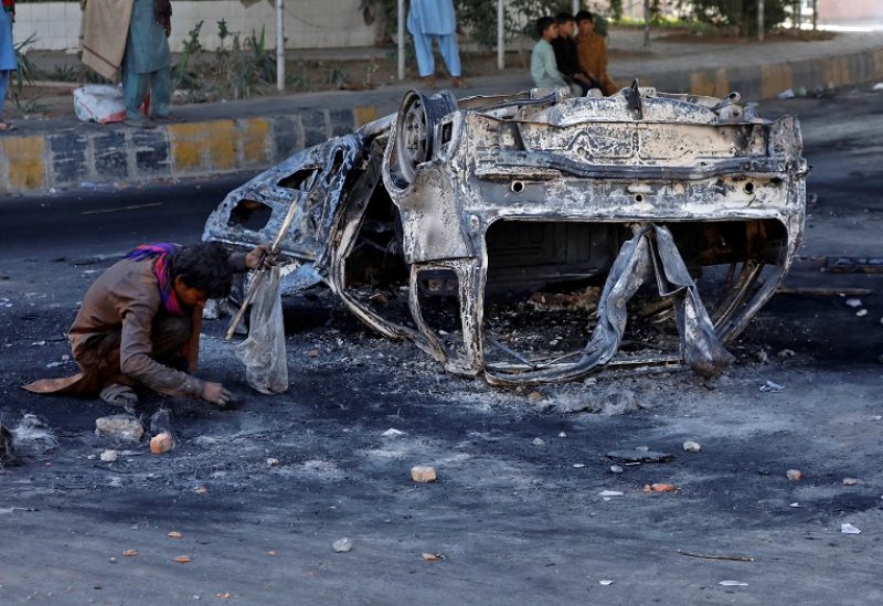 A ragpicker collects usable items next to the debris of a burnt vehicle following a protest by the supporters of Pakistan's former Prime Minister Imran Khan against his arrest, in Peshawar, Pakistan, May 11, 2023. REUTERS/Fayaz Aziz