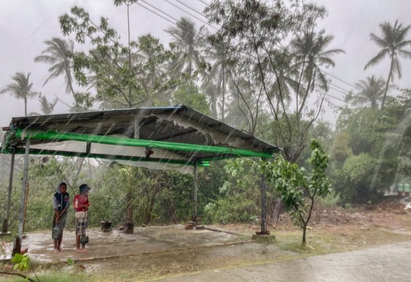 Two children stand under a roadside shelter to protect themselves from rain as Cyclone Mocha approaches Sittwe in Rakhine State, Myanmar on Sunday, May 14, 2023 [AP Photo]