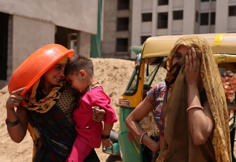 Women take shelter from the sun at a construction site in Ahmedabad, India, April 28, 2023. REUTERS