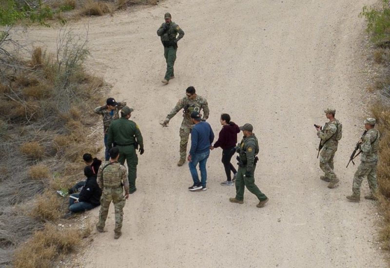 Border patrol agents and Texas Army National Guard soldiers detain migrants, who were hiding in thick brush, after they crossed the Rio Grande river into US - REUTERS