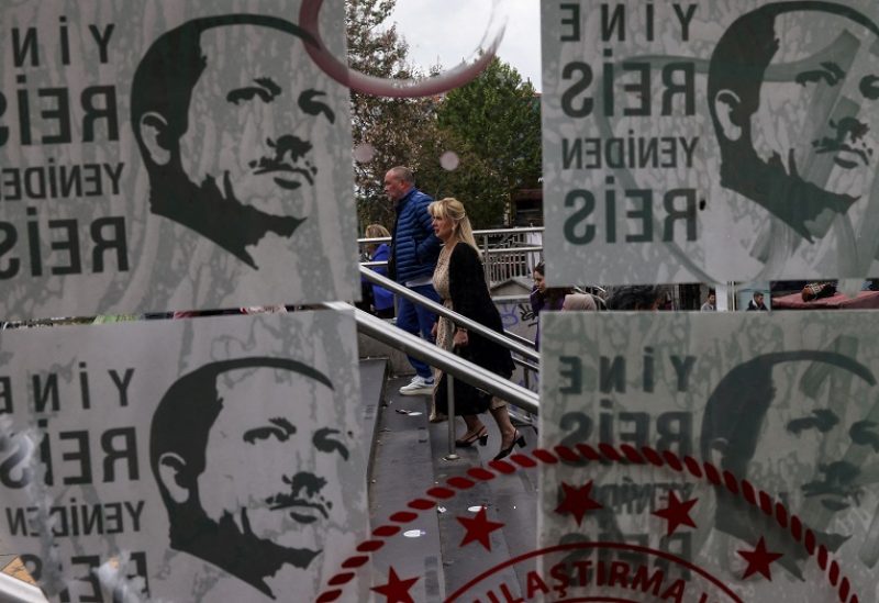 People are seen behind election posters of Turkish President Tayyip Erdogan that read, "The chief again, the chief anew" ahead of the May 14 presidential and parliamentary elections, in Istanbul, Turkey May 11, 2023. REUTERS/Umit Bektas TPX IMAGES OF THE DAY