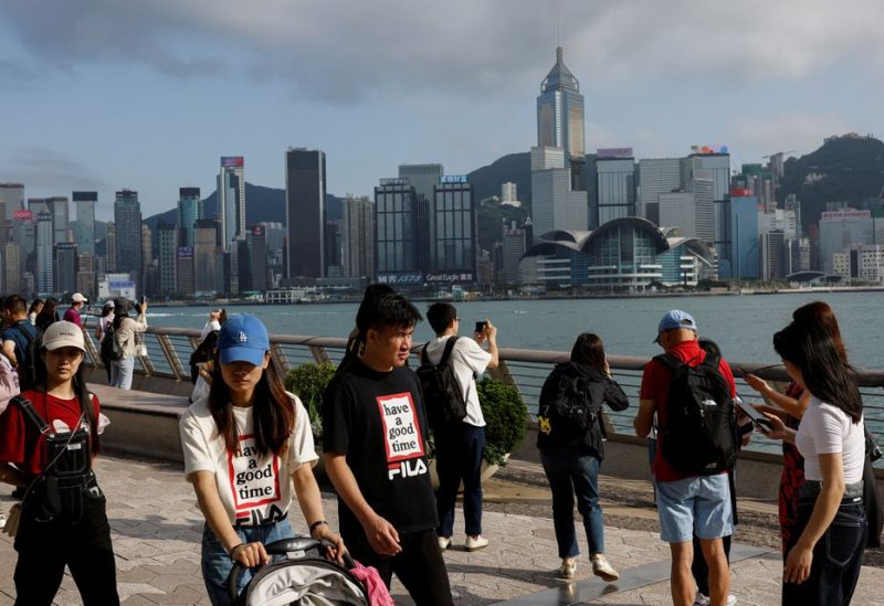 Mainland Chinese tourists walk in front of the skyline of buildings at Tsim Sha Tsui, in Hong Kong, China May 2, 2023. REUTERS