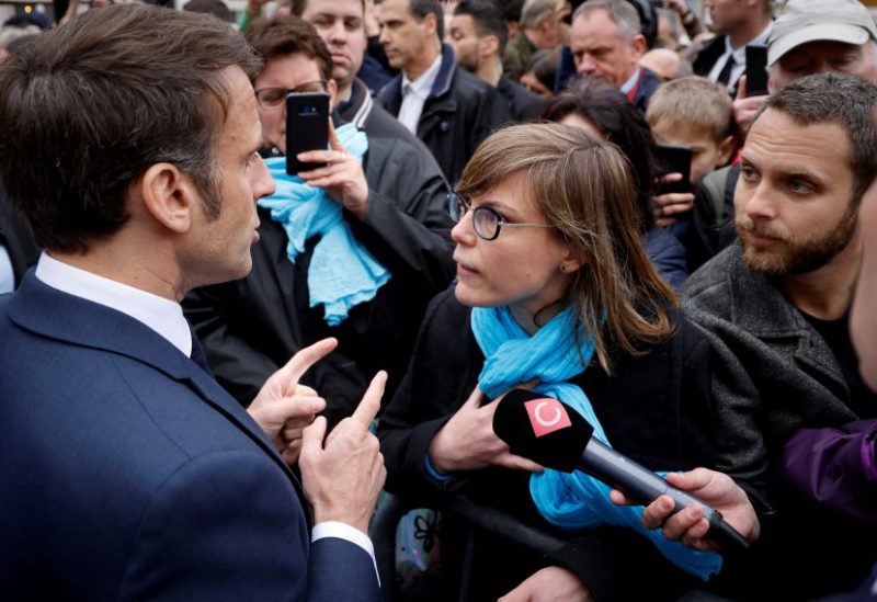 French President Emmanuel Macron talks to a person opposed to the pension reform, in Selestat, eastern France, April 19, 2023. Ludovic Marin/Pool via REUTERS