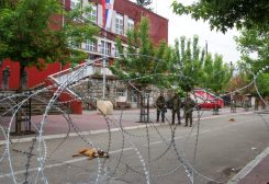 NATO Kosovo Force (KFOR) soldiers stand guard behind razor wire fence in the town of Zvecan, Kosovo, June 5, 2023. REUTERS/Miodrag Draskic.
