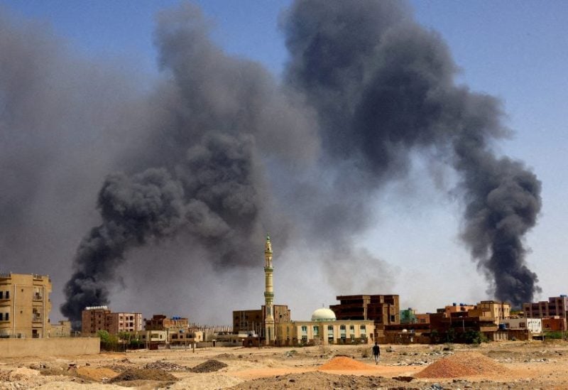 A man walks while smoke rises above buildings after aerial bombardments during clashes between the paramilitary Rapid Support Forces and the army in Khartoum North, Sudan, May 1, 2023. REUTERS/Mohamed Nureldin Abdallah/File Photo