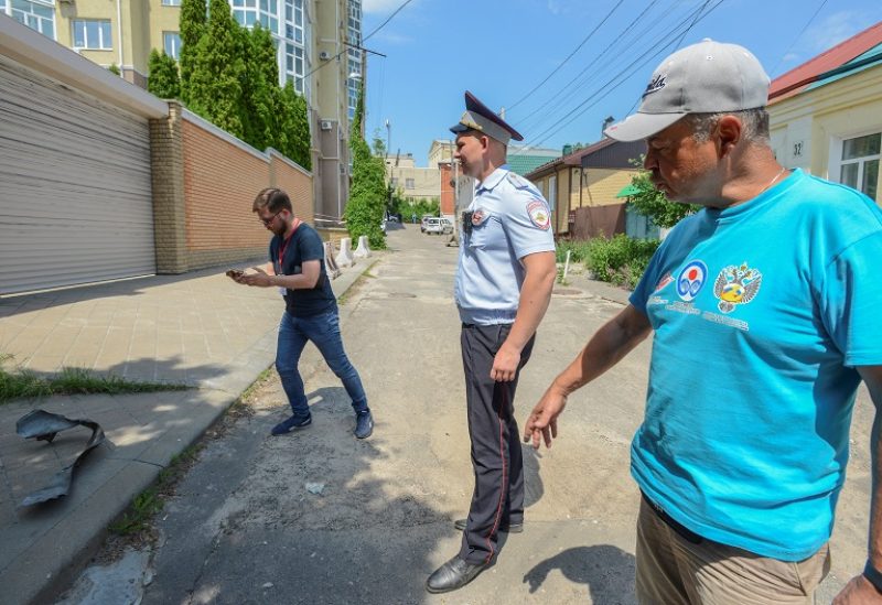 A police officer stands guard as a journalist films near a damaged multi-storey apartment block following a reported drone attack in Voronezh, Russia June 9, 2023. REUTERS/Vladimir Lavrov