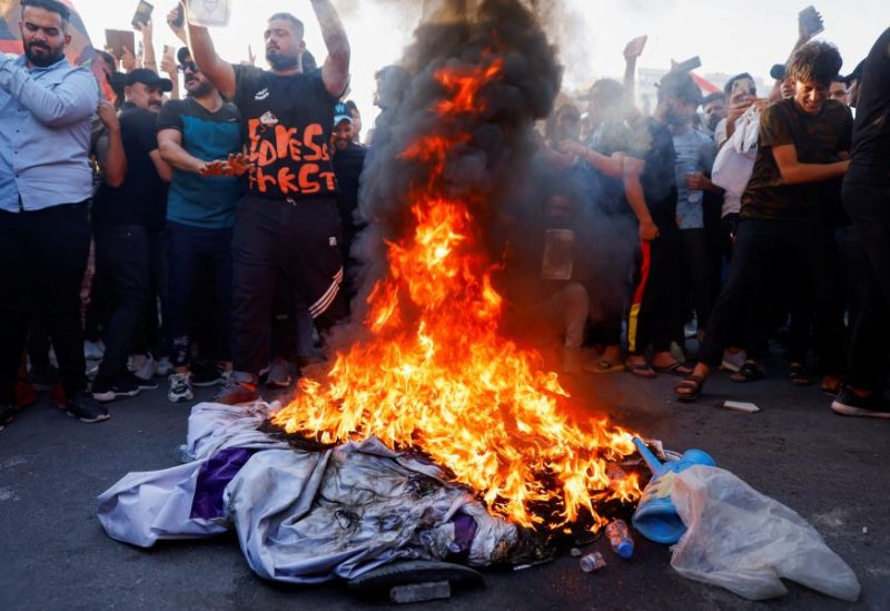 Supporters of Iraqi Shi'ite cleric Moqtada al-Sadr stand in front of a burning banner with the LGBT flag during a protest against a man who tore up and burned a copy of the Koran outside a mosque in the Swedish capital Stockholm, near the Swedish embassy in Baghdad, Iraq, June 30, 2023. REUTERS/Saba Kareem