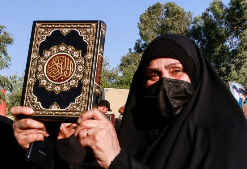 A woman holds a copy of the Koran during a protest against a man who tore up and burned a copy of the Koran outside a mosque in the Swedish capital Stockholm, near the Swedish embassy in Baghdad, Iraq, June 30, 2023. REUTERS/Thaier Al-Sudani