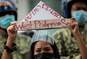 An activist holds a prop with the words "defend West Philippine Sea" during a protest outside the Chinese Consulate in Manila's financial district, guarded by Philippine police, on the anniversary of an international arbitral court ruling invalidating Beijing's historical claims over the waters of the South China Sea, in Makati City, Philippines, July 12, 2021. REUTERS/Eloisa Lopez/File Photo