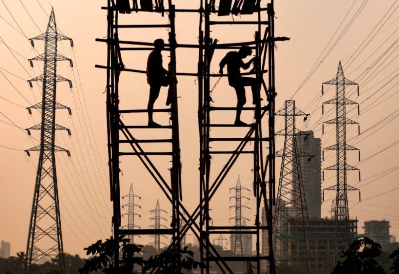 Labourers work next to electricity pylons in Mumbai, India, October 13, 2021. REUTERS/Francis Mascarenhas/File Photo