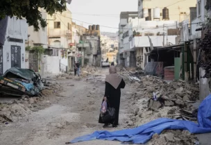 Palestinian woman walks on damaged road in Jenin refugee camp in West Bank, Wednesday, July 5 2023 - AP