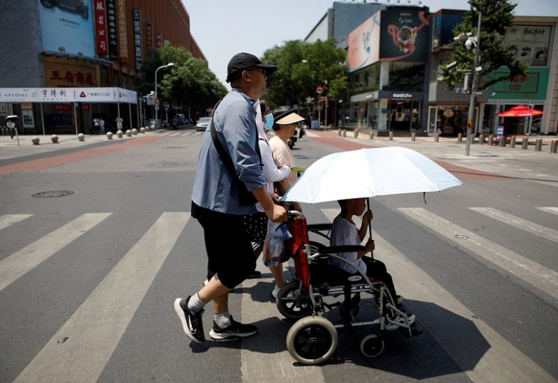 FILE PHOTO: Pedestrians cross a road on a hot day amid an orange alert for heatwave, in Beijing, China June 16, 2023. REUTERS/Florence Lo/File Photo