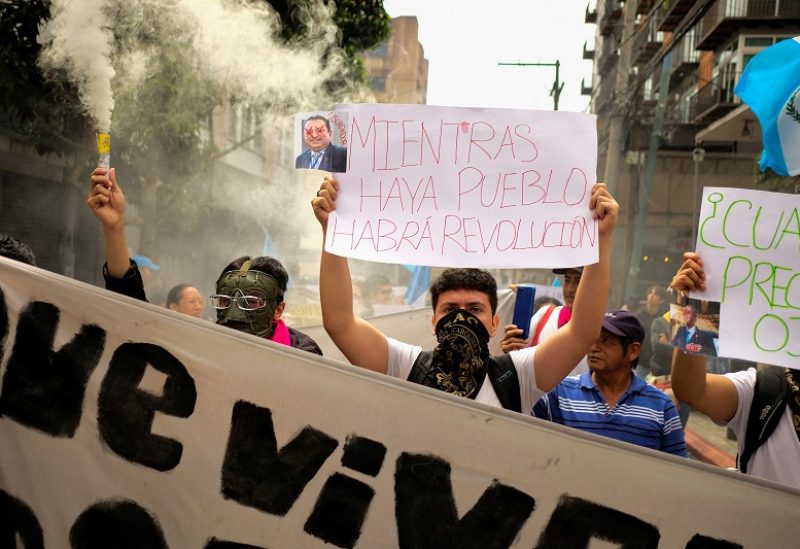 A man holds a sign that reads "while there are people, there will be a revolution", as demonstrators march toward the Supreme Electoral Tribunal (TSE) demanding authorities to respect the voting results of the first round of Guatemala's presidential election, in Guatemala City, Guatemala July 8, 2023. REUTERS/Josue Decavele