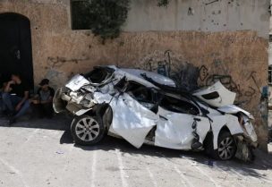 Palestinians sit behind a wrecked car in the occupied West Bank city of Jenin on July 5, 2023, after the Israeli army declared the end of a two-day military operation in the area. The Israeli military launched the raid on the Jenin refugee camp early on July 3, during which 12 Palestinians and one Israeli soldier were killed. (AFP)