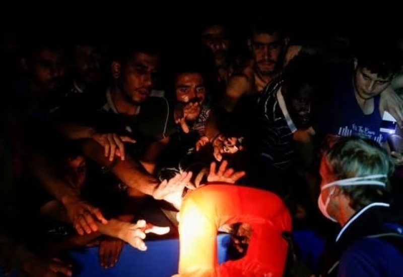 A RHIB (rigid hulled inflatable boat) crew member from the German NGO migrant rescue ship Sea-Watch 3 distributes life jackets to migrants on an overcrowded wooden boat during a rescue operation in international waters off the coast of Tunisia, in the western Mediterranean Sea, August 1, 2021. REUTERS/Darrin Zammit Lupi/File photo