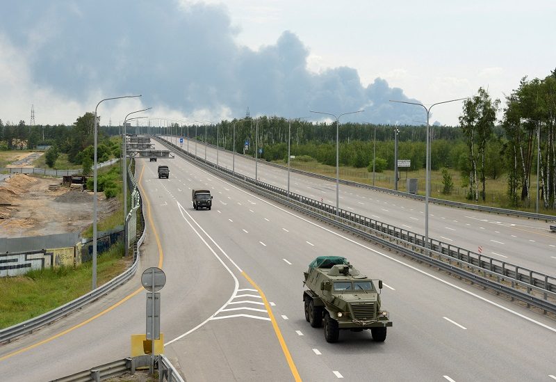FILE PHOTO: A military column of Wagner private mercenary group drives along M-4 highway, which links the capital Moscow with Russia's southern cities, with smoke from a burning fuel tank at an oil depot seen in the background, near Voronezh, Russia, June 24, 2023. REUTERS/Stringer/File Photo