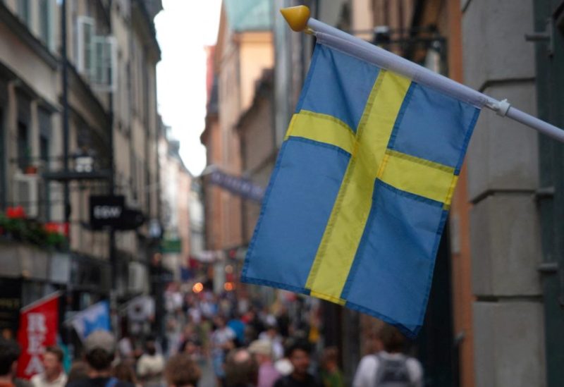 A Swedish flag hangs outside a store on a busy street as visitors walk past in the background in the old town of Stockholm, Sweden, July 14, 2023 REUTERS/Tom Little