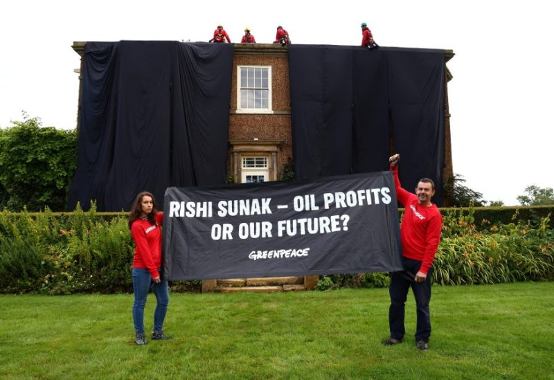 Greenpeace activists hold a banner while others cover British Prime Minister Rishi Sunak's £2m manor house in oil-black fabric in protest of his backing for a major expansion of North Sea oil and gas drilling amidst a summer of escalating climate impacts, in Yorkshire, Britain August 3, 2023. Greenpeace/Handout via REUTERS