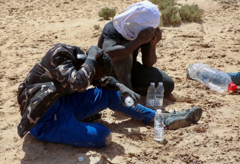 Migrants from Africa sit on the ground as they are stuck in the desert between the Libyan-Tunisian border, near Al-Assah, Libya August 5, 2023. REUTERS/Hazem Ahmed